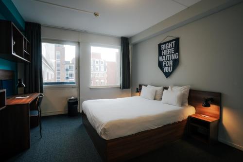 a hotel room with a bed and a sign on the wall at The Social Hub The Hague Extended Stay in The Hague