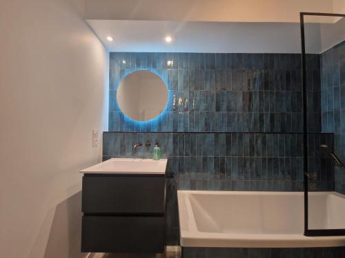 une salle de bain avec un lavabo, une baignoire et un miroir dans l'établissement Appartement avec piscine Bleu du Lac, à Évian-les-Bains