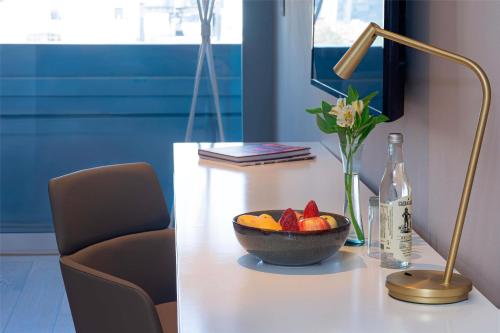 a bowl of fruit on a table with a lamp and a bottle at NH Collection Mexico City Reforma in Mexico City