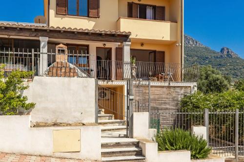 a house with stairs in front of it with mountains at Casa Isolotto D'Ogliastra - vista mare in Lotzorai