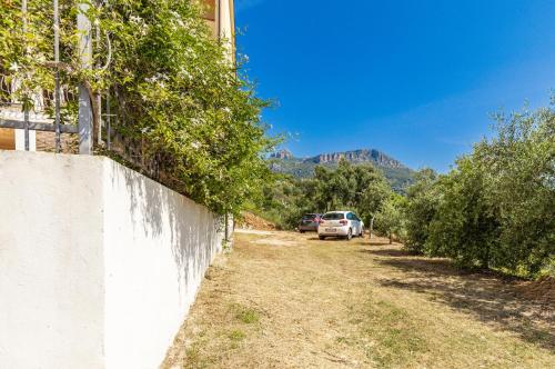 a white car parked next to a wall with trees at Casa Isolotto D'Ogliastra - vista mare in Lotzorai