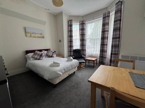Un dormitorio con una cama, un escritorio y una mesa. en Devonshire House Holiday Flats, en Eastbourne