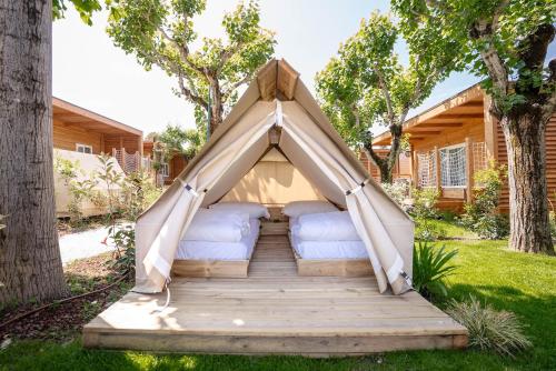 a gazebo with two beds on a wooden deck at Camping Fossalta in Lazise