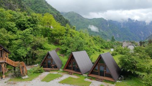 a group of cottages with mountains in the background at Thethi Villas in Theth