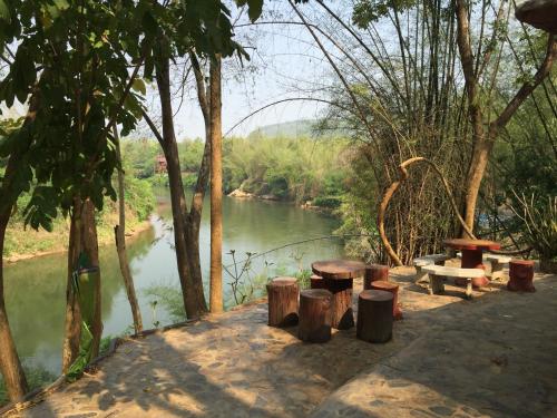 a group of picnic tables next to a river at Saiyok River House in Sai Yok