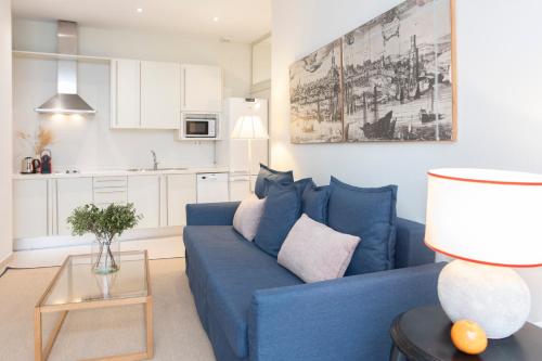 a living room with a blue couch and a kitchen at Alohamundi Chicarreros Catedral in Seville