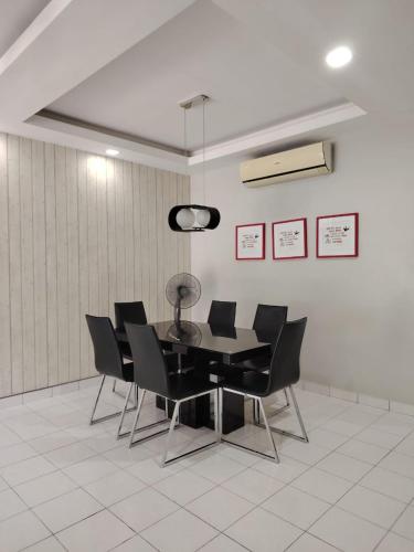 a dining room with a table and black chairs at DIAZ Homestay in Sungai Buluh