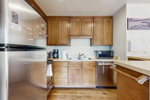 a kitchen with wooden cabinets and a stainless steel refrigerator at Basecamp Bliss in Olympic Valley