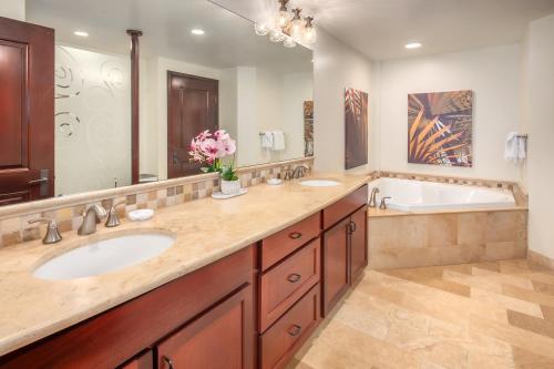un bagno con due lavandini, una vasca e un grande specchio di Waipouli Beach Resort F301 a Wailua