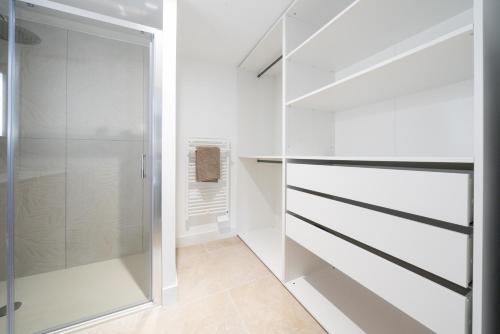 - un dressing avec des armoires blanches et une porte en verre dans l'établissement Maisons PontLac, 2 maisons reliées en bord de canal à Cazaux, à La Teste-de-Buch