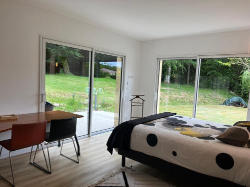 a bedroom with a bed and a desk and windows at Maison au vert-Entre-Deux-Mers, Repos et confort au coeur de la nature in Cursan