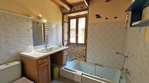 ein Badezimmer mit Badewanne, Waschbecken und Toilette in der Unterkunft La petite maison in Château-Chervix
