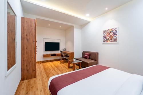 a bedroom with a bed and a desk and a television at Basotel Hotel Indore Vijaynagar in Indore