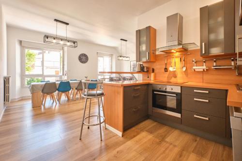 - une cuisine avec des placards en bois et des tabourets de bar bleus dans l'établissement Grande Maison De Ville Renove, à Villard-de-Lans