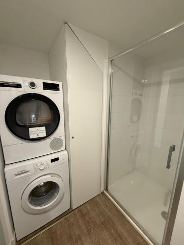 La salle de bains est pourvue d'un lave-linge et d'une douche. dans l'établissement L'Amandier - Joli appartement T3 neuf centre ville à 2 pas de la Rotonde Mirabeau et des Allées Provençales, à Aix-en-Provence