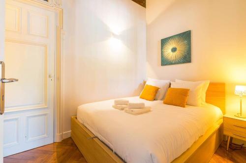 - une chambre avec un grand lit blanc et des oreillers jaunes dans l'établissement L'Atre des Ducs, au centre historique de la ville, à Dijon