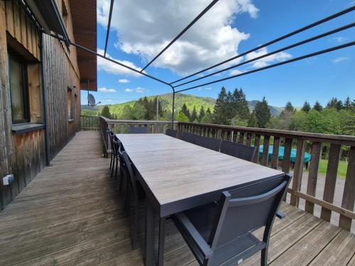 a wooden deck with a table and chairs at Chalet Les Plombes - isolé, Jacuzzi, Piscine in Xonrupt-Longemer