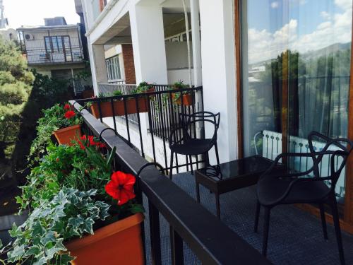 a balcony with chairs and red flowers and plants at Tbilisi View Hotel in Tbilisi City