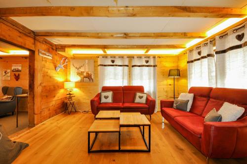 a living room with two red couches and a table at Chalet La Scie in Morgins