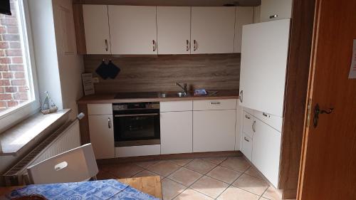 une petite cuisine avec des armoires blanches et un évier dans l'établissement FeWo Nr 1 - 4-Personen, à Schlagsdorf