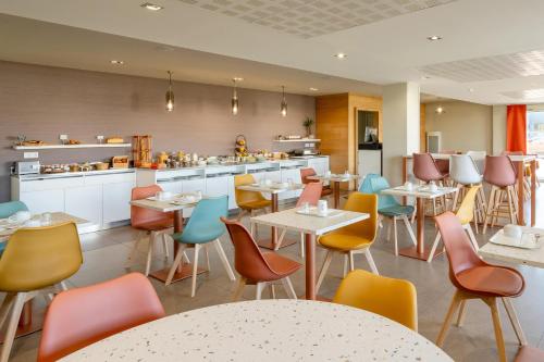 un restaurant avec des tables et des chaises et une cuisine dans l'établissement Sure Hotel by Best Western Rennes Chantepie, à Chantepie