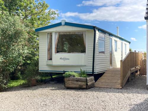 a tiny caravan with a porch and a deck at Clashmore Wood in Dornoch
