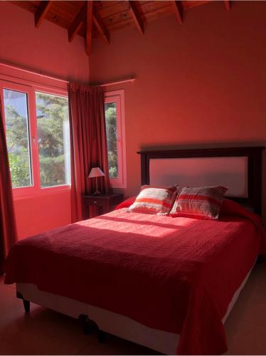 a red bedroom with a bed with red sheets and pillows at Valeria Beach in Valeria del Mar