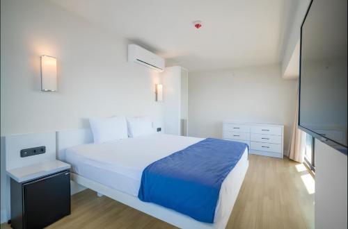 a white bedroom with a bed and a television at Batumi black sea view central Hotel in Batumi