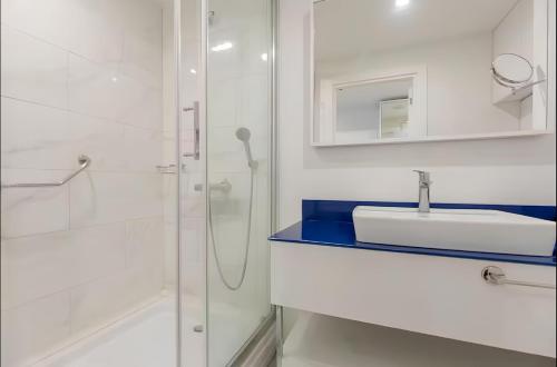 a white bathroom with a sink and a shower at Batumi black sea view central Hotel in Batumi