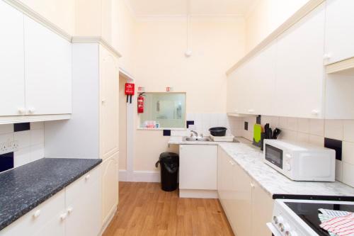 a kitchen with white cabinets and a microwave at Brookvale Guest House Room 15 in Southampton