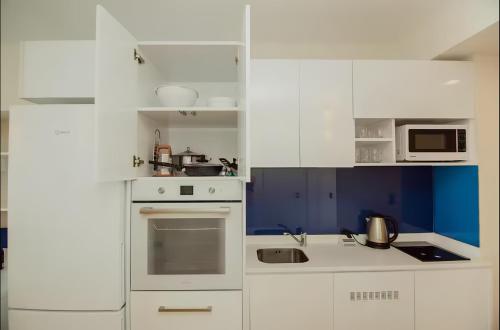 a white kitchen with white cabinets and appliances at Batumi black sea view central Hotel in Batumi