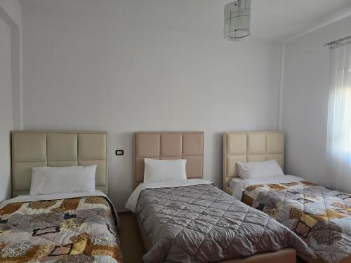 two beds in a room with white walls at Sun& Relax Home in Korçë