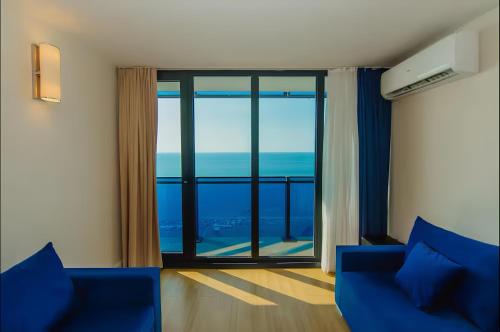 a room with a blue couch and a large window at Batumi black sea view central Hotel in Batumi