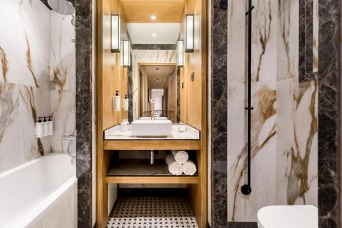 une salle de bain avec une baignoire, un lavabo et un miroir dans l'établissement Merveil - Signature Suite - Tour Eiffel -Desaix II, à Paris