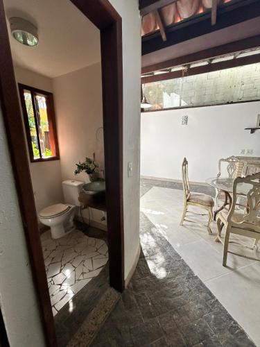 a bathroom with a toilet and a table and chairs at Casa Quinta do Atlântico - Aconchego da Paz 150m da praia in Búzios