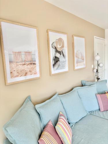 un salon avec un canapé bleu avec des tableaux sur le mur dans l'établissement Golf et sentiers côtiers GR34, à Carantec