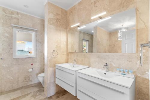 a bathroom with two sinks and a toilet at Upscale Ocean View Villa with Pool Outdoor Kitchen in Palm-Eagle Beach