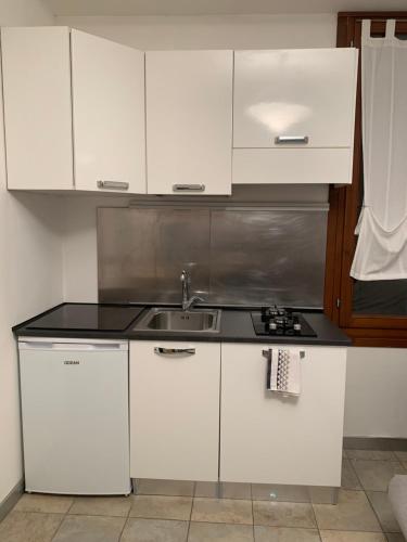 une cuisine avec des armoires blanches et un évier dans l'établissement Casa Manuela non turisti ma ospiti, à Chioggia