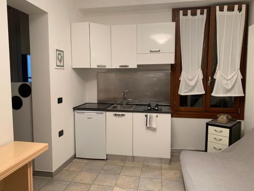 une petite cuisine avec des armoires blanches et un évier dans l'établissement Casa Manuela non turisti ma ospiti, à Chioggia