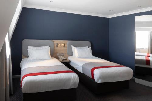two beds in a room with blue walls at Holiday Inn Express London Victoria by IHG in London