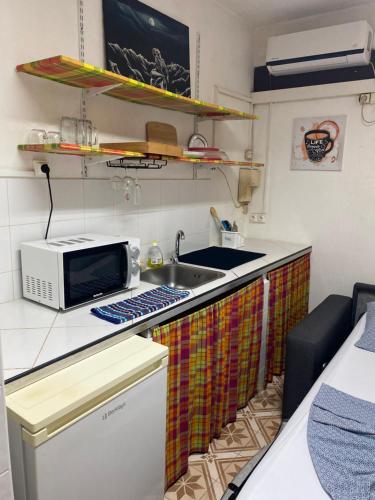 a small kitchen with a sink and a microwave at Petit coin posé in Saint-Laurent du Maroni