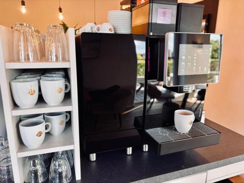 a counter with cups and a coffee maker at stilfrei by Humble Homes in Carolinensiel