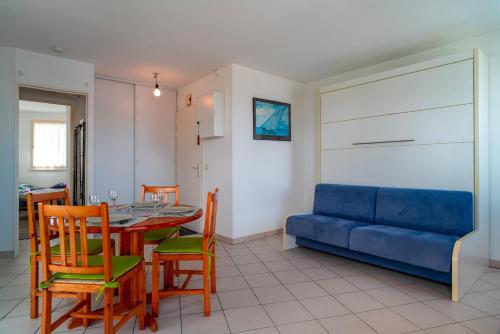 un salon avec une table et un canapé bleu dans l'établissement Le 47°N Crouesty - appt proche de la plage, à Arzon