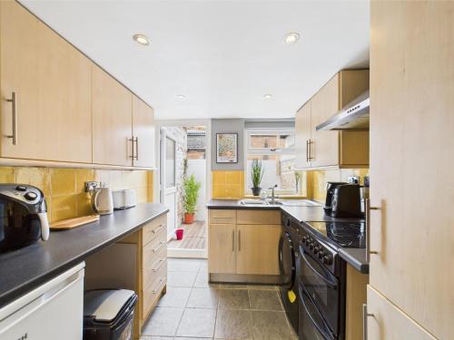 a kitchen with wooden cabinets and black appliances at 2-Bed Cheltenham Town Centre Kings Row - Free Permit Parking in Cheltenham