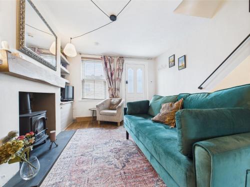 a living room with a green couch and a fireplace at 2-Bed Cheltenham Town Centre Kings Row - Free Permit Parking in Cheltenham