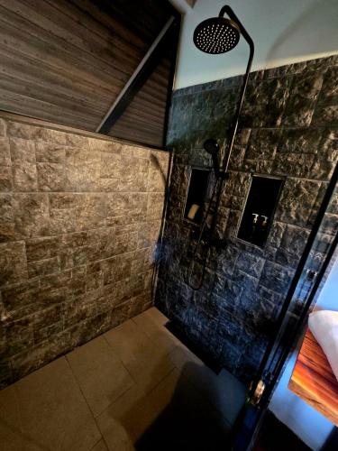 a shower in a room with a stone wall at Jungle River Resort in Ojochal