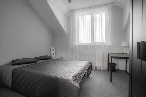 a white bedroom with a bed and a window at Vėjo Malūnų sodyba - Didžioji vila in Paserninkai
