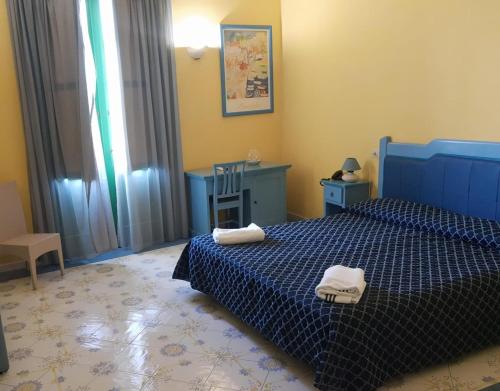 a bedroom with a blue bed with towels on it at Hotel Savoia in Procida