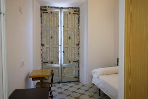 a room with a door with a table and a bed at Pigal in Tarragona