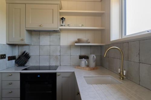 a kitchen with white cabinets and a sink and a window at Fritton Lake Retreats in Fritton Norfolk